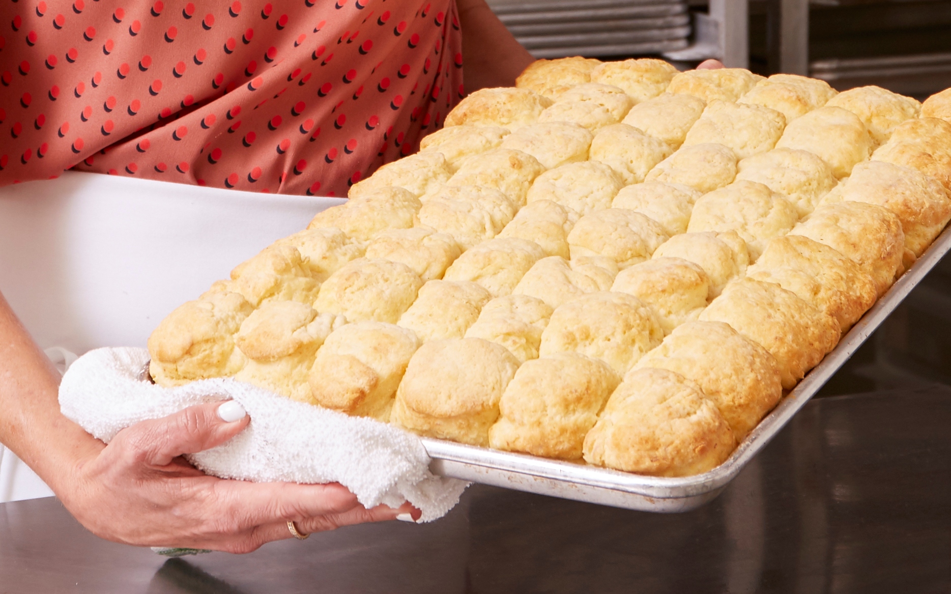 baker holding pan of biscuits 