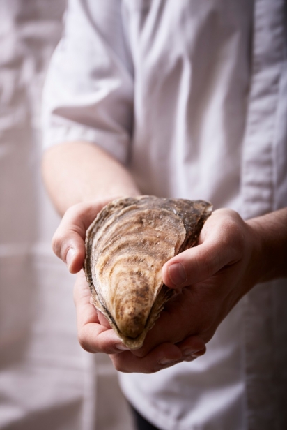 A large oyster in the hands of Chef Romo