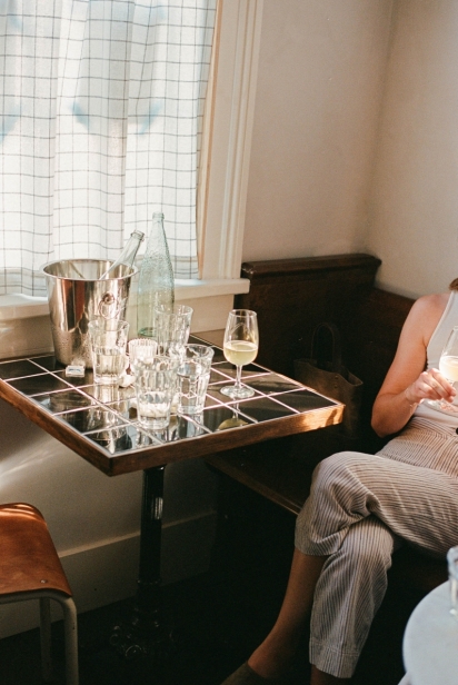 woman sits on couch near table with wine glasses