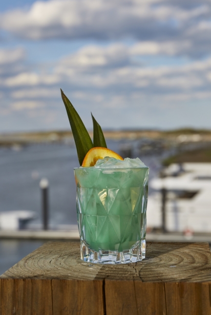 turquoise drink sits near the water 