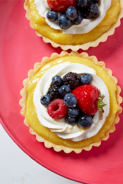 lemon tart with berries on a red platter