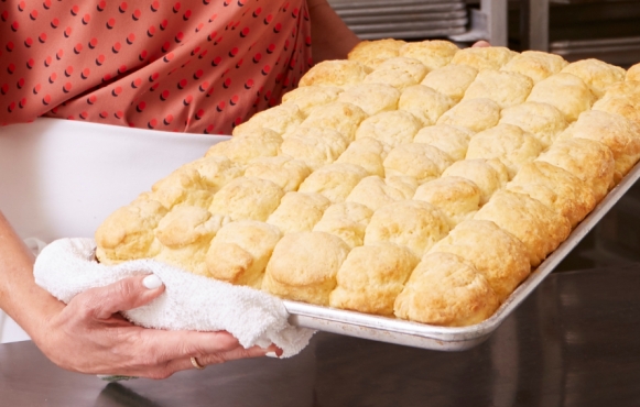 baker holding pan of biscuits 