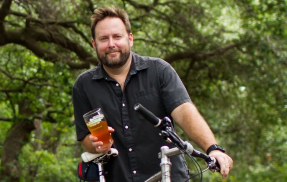 Brewer on a bike holding a beer