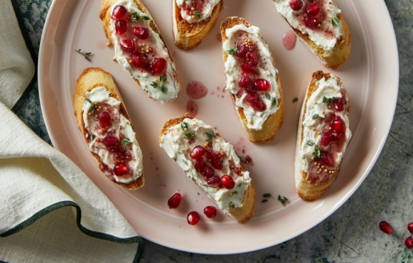 A plate of bread slices topped with pomegranate seeds