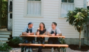 three people sit at a picnic table and drink wine